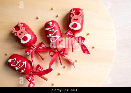 Flache Schicht von Kuchen Pops Eis auf einem Stock in rosa Glasur mit Erdbeeren und Heidelbeeren auf hellem Hintergrund. Stockfoto
