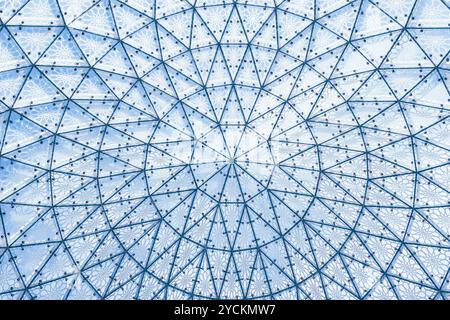 Architektonische Glasstruktur mit geometrischem Dreiecksmuster auf blauem Himmel. Stahlglasdach des Gebäudes, durchsichtiges Dachfenster Stockfoto