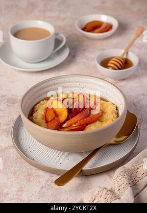 Lebensmittelfotografie von Hirsebrei mit karamelisiertem Pfirsich, Nektarine mit Agavendicksaft, Honig, Tee mit Mandelmilch Stockfoto