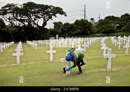 Ein Angestellter, der die Kreuze auf dem Manila American Cemetery reinigt, für US-Soldaten, die während des Zweiten Weltkriegs getötet wurden, Fort Bonifacio, Taguig, Philippinen. Stockfoto