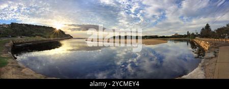 Panoramablick am Eingang der Narrabeen Seen am frühen Morgen mit Sonnenschein über der Landzunge North Narrabeen. Narrabeen Surfclub rechts. Der See schlängelt sich aus Stockfoto