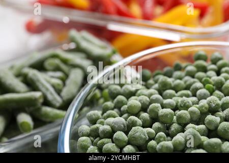 Gefrorene grüne Erbsen in Glasschale auf verschwommenem Hintergrund, Nahaufnahme Stockfoto