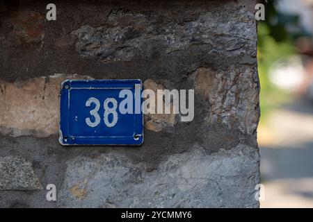 Zahl 38 in Blau: Weiße Zahlen auf Metallplatte um die verschwommene Ecke Stockfoto