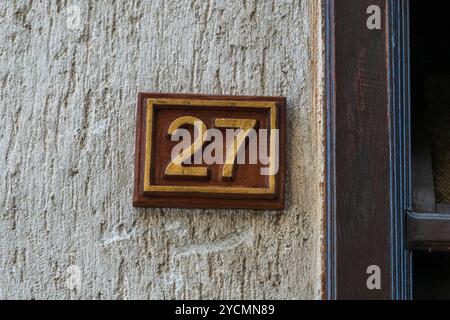 Nummer 27 auf einem hölzernen braunen quadratischen Brett: Ein einfaches Außendetail vor der Haustür. Stockfoto