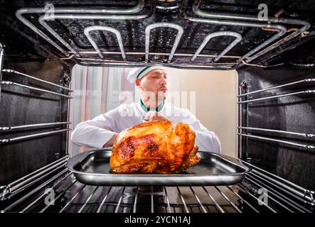 Chefkoch gebratenes Huhn in den Ofen, Blick aus dem Inneren des Ofens. Kochen in den Ofen. Stockfoto