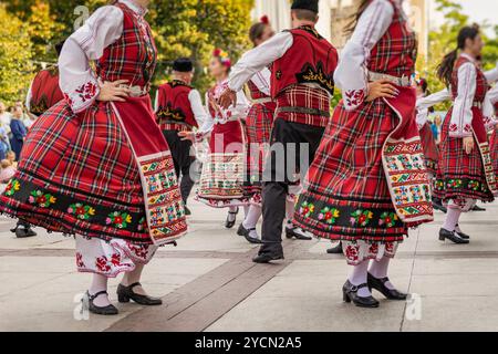 Eine Gruppe von Tänzern zeigt traditionellen Volkstanz in farbenfrohen Kostümen, lebhafte Aufführungen unter dem Himmel Stockfoto