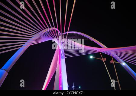 Diese fesselnde Fotoserie zeigt eine atemberaubende moderne Brücke, die mit einer lebendigen Lichtanzeige beleuchtet wird. Stockfoto