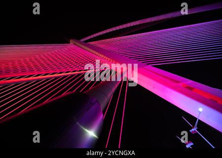 Diese fesselnde Fotoserie zeigt eine atemberaubende moderne Brücke, die mit einer lebendigen Lichtanzeige beleuchtet wird. Stockfoto