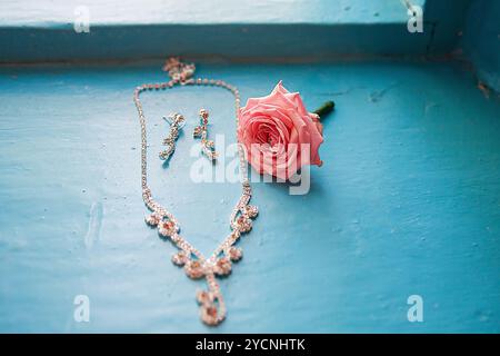 Elegante Rose mit Halskette und Ohrringen auf einem Blau Stockfoto