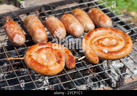 Leckere Schweine- und Rindfleisch Würstchen über glühende Kohlen auf dem Grill Feuer kochen Stockfoto