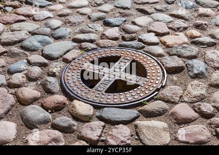 Alten Stahl Kanalisation Kanaldeckel auf der gepflasterten Straße. Text auf Russisch: städtische Kanalisation Stockfoto