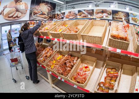 SAMARA, RUSSLAND - 5. OKTOBER 2014: Junge Frau, die frische Backwaren beim Einkaufen im Supermarkt Magnit wählt. Russlands l Stockfoto