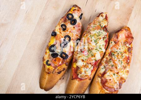 Assorti Bruscjetta mit Wurst, Käse, Tomaten aus großem weißem Baguette auf hölzernem Hintergrund Stockfoto