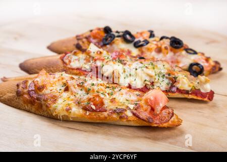 Assorti Bruscjetta mit Wurst, Käse, Tomaten aus großem weißem Baguette auf hölzernem Hintergrund Stockfoto