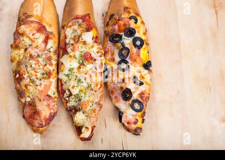 Assorti Bruscjetta mit Wurst, Käse, Tomaten aus großem weißem Baguette auf hölzernem Hintergrund Stockfoto