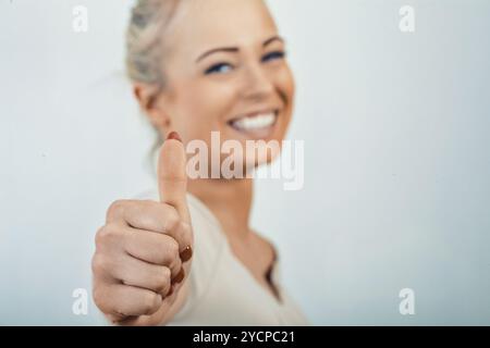 Nahaufnahme einer Frauenhand, die den Daumen nach oben zeigt und Glück und Erfolg in einem Unternehmen vor weißem Hintergrund vermittelt Stockfoto