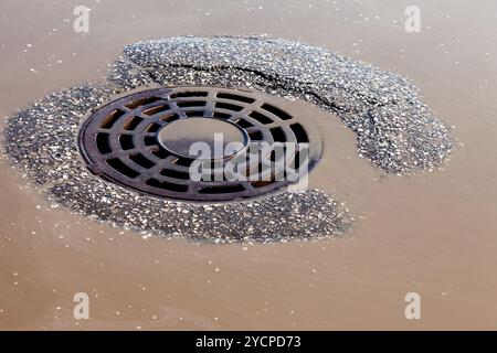 Geschmolzene Wasser fließt durch die Schachtabdeckung auf Frühling Stockfoto