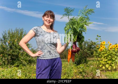 Junge Frau, die eine Garbe von Gemüse in der Hand halten Stockfoto