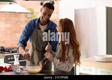 Zusammen in der Küche backen, ein Multiracial-Paar bereitet mit Freude Urlaubsfreuden vor, zu Hause Stockfoto