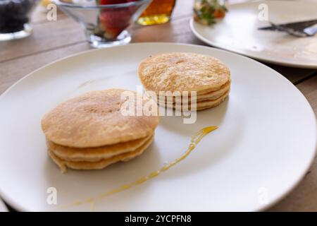 Pfannkuchen auf Teller mit Sirup, frische Beeren im Hintergrund, Frühstückseinrichtung, zu Hause Stockfoto