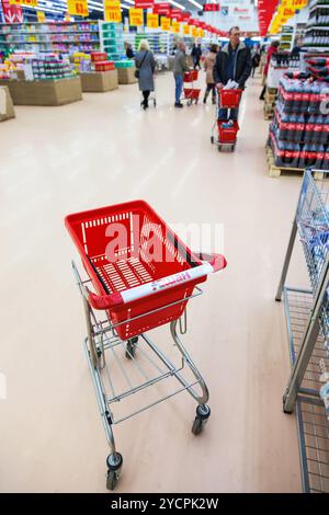Leerer roter Einkaufswagen im Innern des Auchan Stores Stockfoto