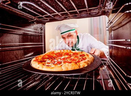 Koch kocht Pizza im Ofen. Stockfoto