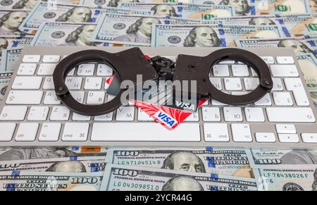 Stahl Handschellen und Kreditkarten auf einer Computertastatur auf dem Hintergrund der US-Dollar liegen Stockfoto