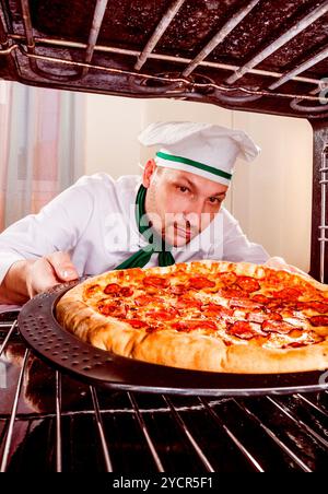 Koch kocht Pizza im Ofen. Stockfoto