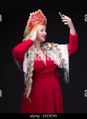 Mädchen, das in traditioneller russischer Tracht mit Handy steht Stockfoto