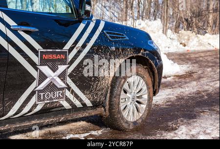 SAMARA, RUSSLAND - 14. FEBRUAR 2016: Vorderteil des Autos Nissan Patrol mit dreckigem Rad auf der Landstraße am Wintertag Stockfoto