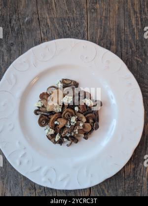 Ein Pilzsalat mit Blauschimmelkäse auf einem weißen Teller Stockfoto