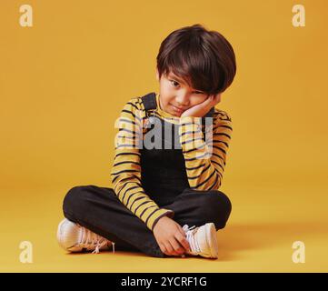 Gelangweilt, einsam und Porträt mit asiatischem Jungen auf gelbem Hintergrund, isoliert im Studio für Wachstum. ADHS, Depression oder Traurigkeit und stimmungsvolles Kind auf dem Boden Stockfoto