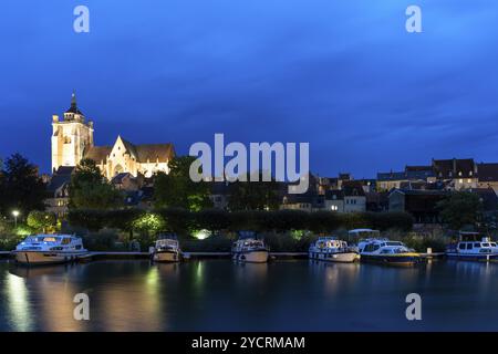 Dole, Frankreich, 14. September 2022: Nächtlicher Blick auf die beleuchtete katholische Kirche Notre Dame in Dole mit Hausbooten auf dem Doubs River im Foregr Stockfoto