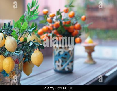 Zweig mit Zitronen, Mandarinen in Keramikvase auf dem Tisch. Traditionelles Muster, Sizilien, Italien. Obst und Einrichtung. Stockfoto