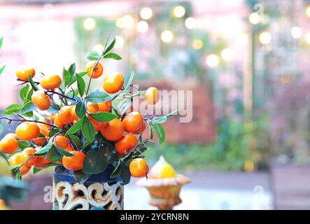 Zweig mit Mandarinen in Keramikvase auf dem Tisch. Traditionelles Muster, Sizilien, Italien. Obst und Einrichtung. Stockfoto