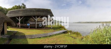 Wexford, Irland, 18. August 2022: Typisches Viking Long House mit einem rekonstruierten Boot am Ufer des Flusses Slaney im Irish National Heritage Stockfoto