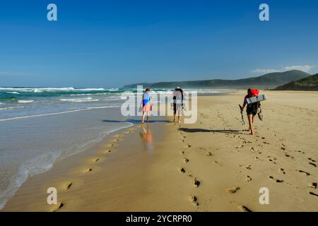 Drei Personen zu Fuß über den Sandstrand von Nature&#39;s Valley, Otter Trail, Tsitsikamma Section, Garden Route National Park, Eastern Cape, South Stockfoto