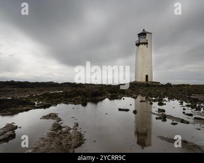 Ein Blick auf den historischen Southerness Lighthouse in Schottland mit Reflexionen in Gezeitenbecken im Vordergrund Stockfoto