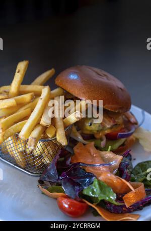 Ein vertikaler Blick auf köstliche Cheeseburger und pommes Frites in einem Korb mit Beilage aus frischem Gemüse Stockfoto