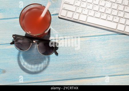 Weiße moderne Tastatur mit Strandaccessoires auf blauem Holztisch Stockfoto