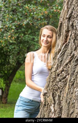 Nahaufnahme nachdenkliche junge Naturliebhaberin, die einen riesigen Baum umarmt Stockfoto