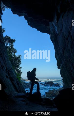 Frau wandert in Guano Cave und blickt auf das Meer, Otter Trail, Tsitsikamma Section, Garden Route National Park, Eastern Cape, Südafrika Stockfoto