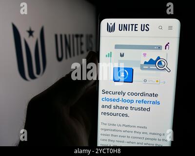 Person, die ein Mobiltelefon hält, mit der Webseite des Sozialunternehmens Unite USA Inc. (Unite US) auf dem Bildschirm mit Logo angezeigt wird. Konzentrieren Sie sich auf die Mitte des Telefondisplays. Stockfoto