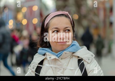Schöne Frau mit orientalischem Aussehen 40 - 45 Jahre alt auf dem Hintergrund einer verschwommenen Stadtlandschaft. Stockfoto