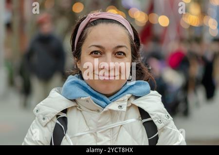 Schöne Frau mit orientalischem Aussehen 40 - 45 Jahre alt auf dem Hintergrund einer verschwommenen Stadtlandschaft. Stockfoto