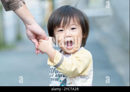 Der Junge blickt zurück und hält die Hände mit seiner Mutter Stockfoto