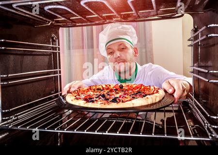 Koch kocht Pizza im Ofen. Stockfoto