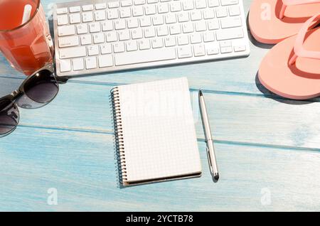 Weiße moderne Tastatur mit Strandaccessoires auf blauem Holztisch Stockfoto