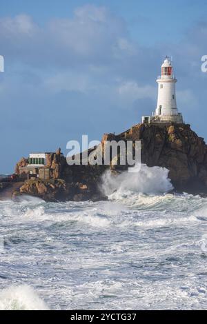 Der Leuchtturm La Corbiere auf einer felsigen Insel während eines Sturms und der Flut. Hohe Wellen krachen gegen Felsen. Stockfoto