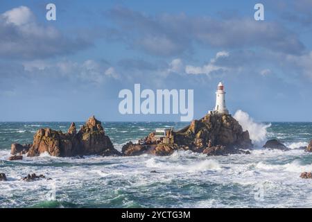 Der Leuchtturm La Corbiere auf einer felsigen Insel während eines Sturms und der Flut. Hohe Wellen krachen gegen Felsen. Stockfoto